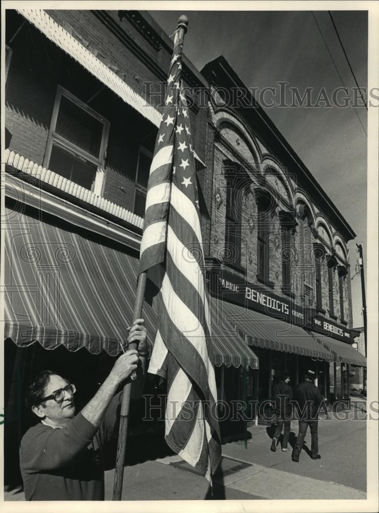 1997 Press Photo Spenser Benedict raises flag in front of his Darlington, store. - Historic Images