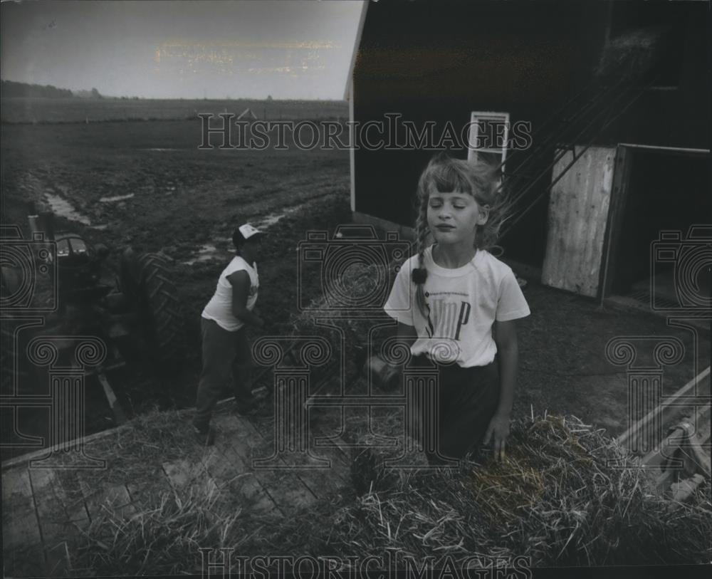 1993 Press Photo Wind cools Destinee Jaeger off helping Tony Leoh load hay bales - Historic Images