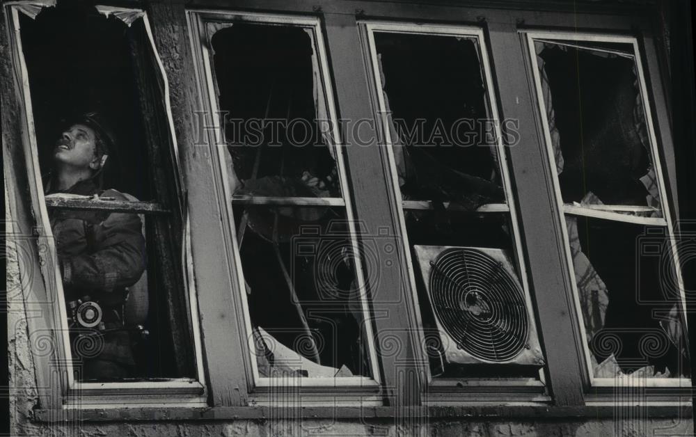 1986 Press Photo A firefighter vents a room after a blaze in Milwaukee - Historic Images