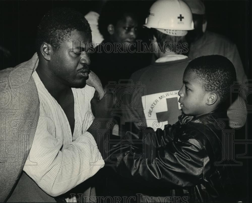 1988 Press Photo Boy helped Barry James put on coat at scene of fire - Milwaukee - Historic Images