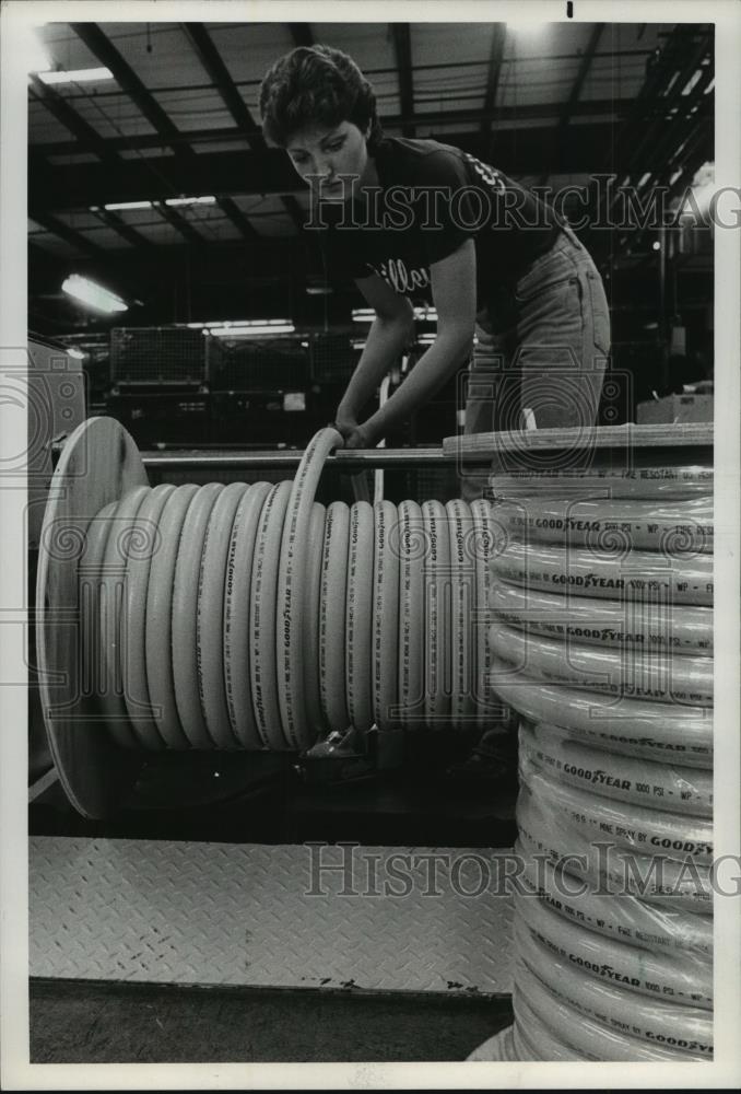 1983 Press Photo Goodyear Plant Employee Prepares Mine Spray Hose for Shipment - Historic Images