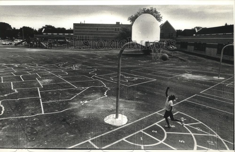 1991 Press Photo Young Leslie Dysart shoots hoops on Pluto's school playground - Historic Images