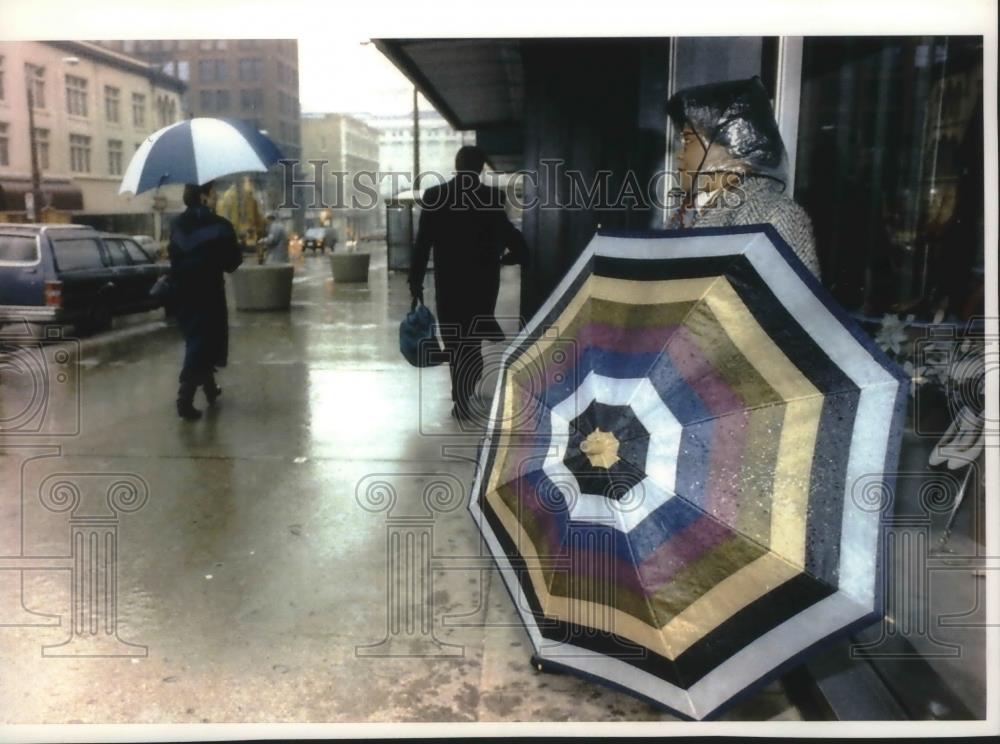 1993 Press Photo Taking shelter from the rain while waiting for a bus, Milwaukee - Historic Images
