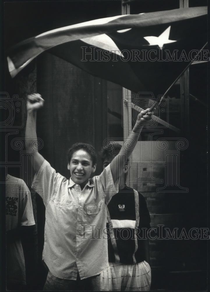 1990 Press Photo Edwin Acevedo of Milwaukee waves Puerto Rican flag in parade. - Historic Images
