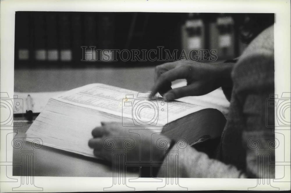 1993 Press Photo Librarian checks reference book for a caller in Milwaukee. - Historic Images