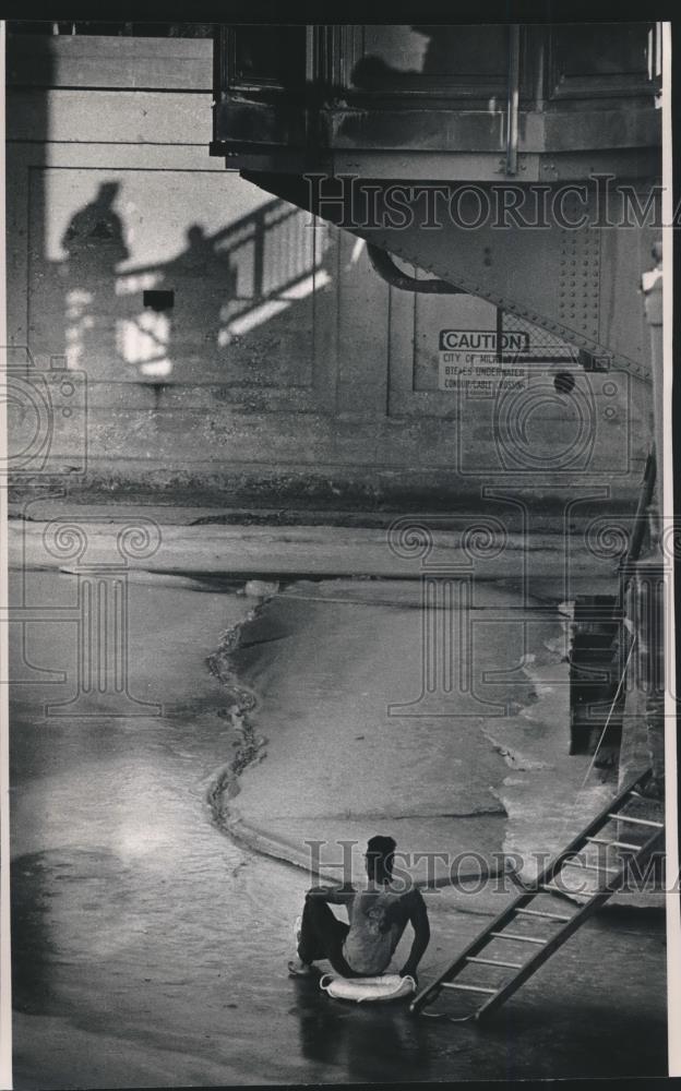 1992 Press Photo Man sits on life ring under bridge in icy Milwaukee River - Historic Images