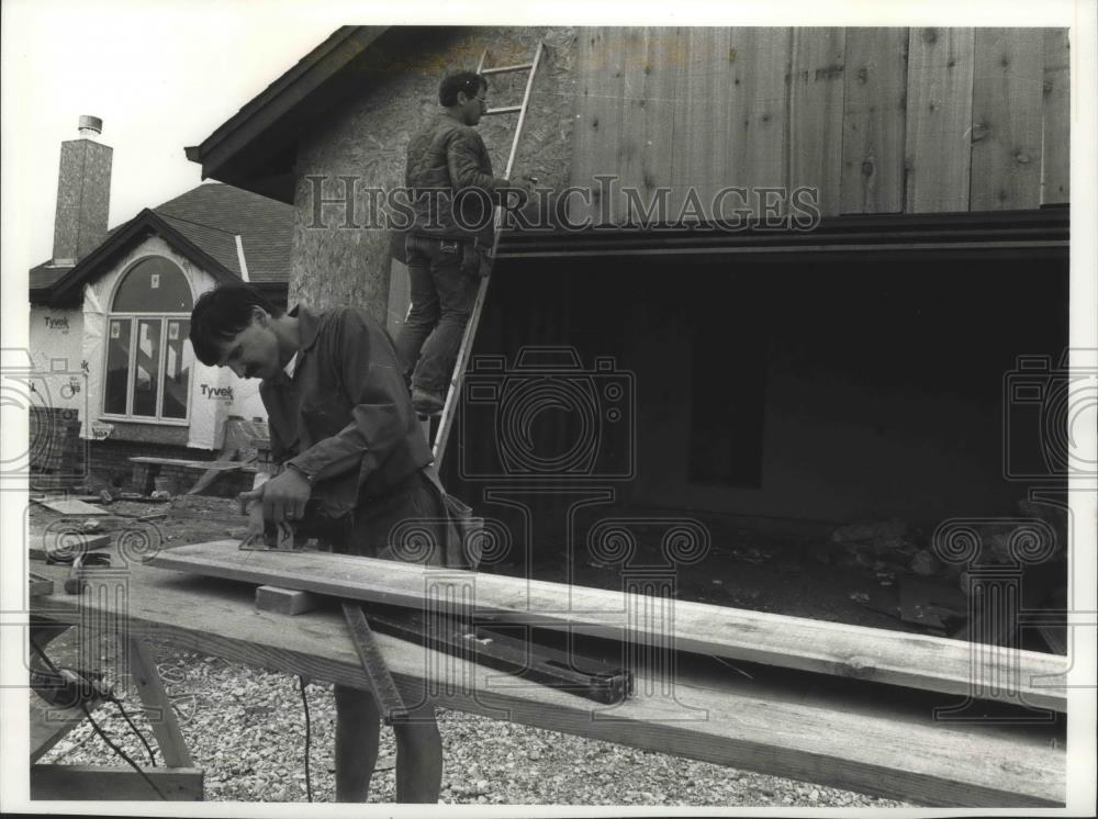 1989 Press Photo Paul Brody saws lumber as other worker does siding, Wisconsin. - Historic Images