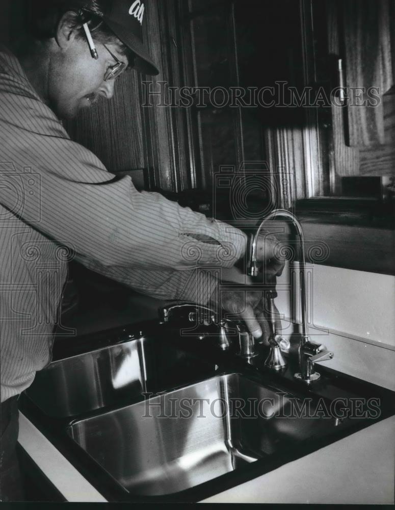 1993 Press Photo Mat Mathson a plumber installs a faucet on stainless steel sink - Historic Images