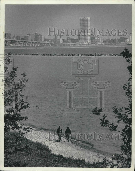 1977 Press Photo View of men walking on beach, with skyline of city, Milwaukee. - Historic Images