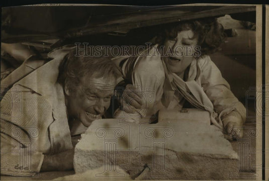 Press Photo Charlton Heston and Ava Gardner hide under a car in a film - Historic Images