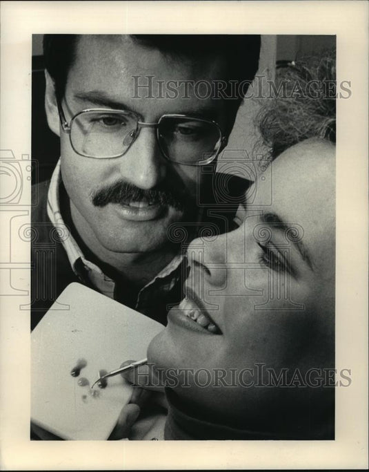 1986 Press Photo Dentist Barry Wolf applying Christmas design on patient's tooth - Historic Images
