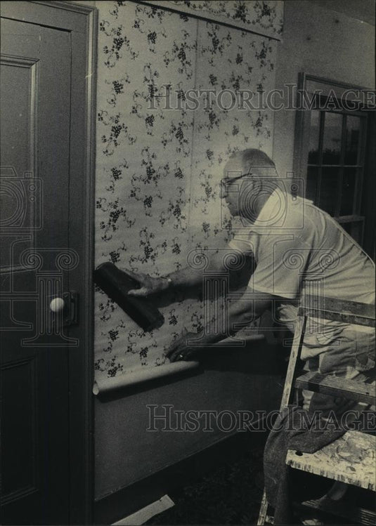 1983 Press Photo Don Coyle hangs a strip of clay-based wallpaper in Benson House - Historic Images