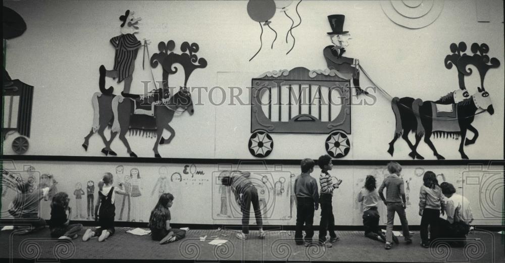 Artists draw families under mural at Elm Creative Art School, 1985