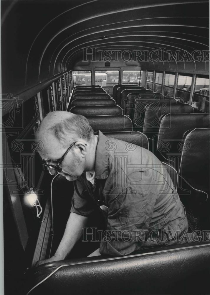 1984 Press Photo Marlon Krukar checks seats at Golden Rule Bus Company Milwaukee - Historic Images
