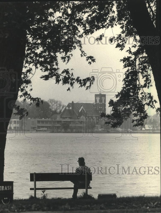 1987 Press Photo Fisherman On Bench Along Fowler Lake In Downtown Oconomowoc - Historic Images