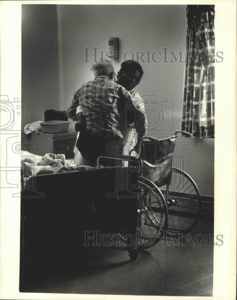 1986 Press Photo Nurse's aide Bernice Jefferson helps patient to wheelchair - Historic Images