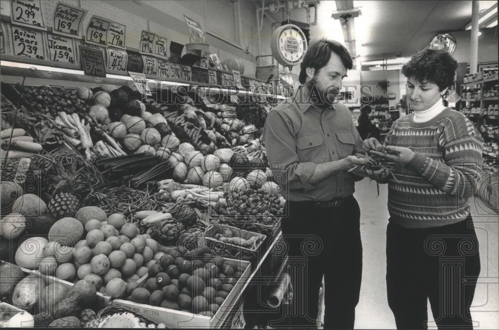 1989 Press Photo Employees at Outpost Natural Foods Cooperative look at beans - Historic Images