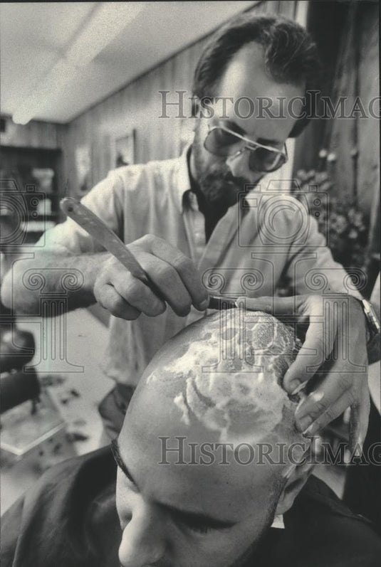 1985 Press Photo Mukwonago Village Player, Dums, shaving Dan Hargarten's head. - Historic Images
