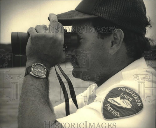 1987 Press Photo Pewuakee Lake Officer Iding scanning lake with binoculars - Historic Images