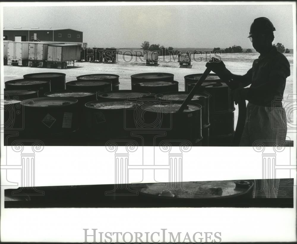 Press Photo Unidentified worker drains hazardous waste in Emelie, Alabama - Historic Images