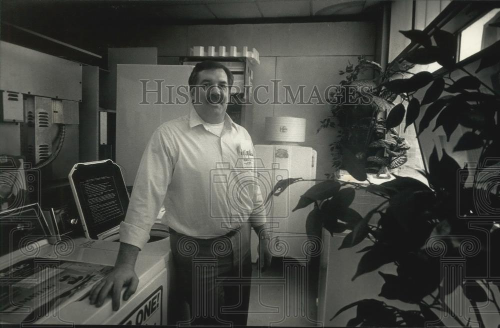 1992 Press Photo Gene Scheunemann next to laundry machine in Jackson, Wisconsin - Historic Images