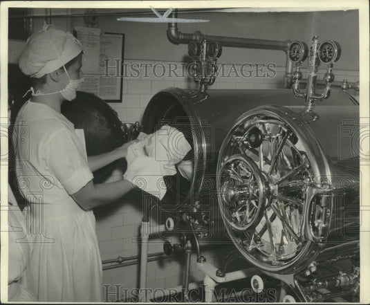 Press Photo Hospital worker sterilizing garments with sterile hands. - Historic Images