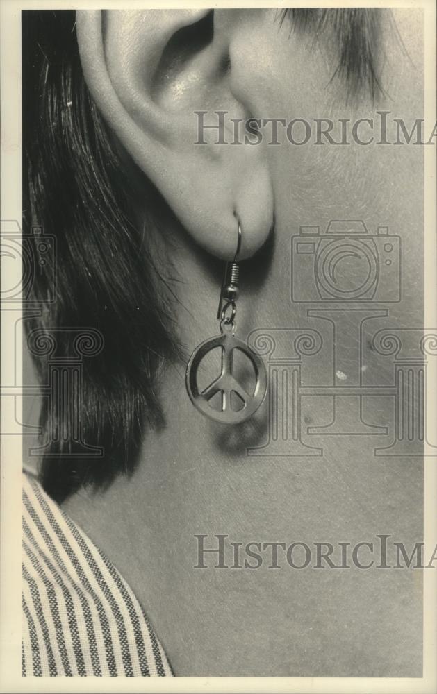 1989 Press Photo Model wears a peace symbol earring as promotion - mjb83080 - Historic Images