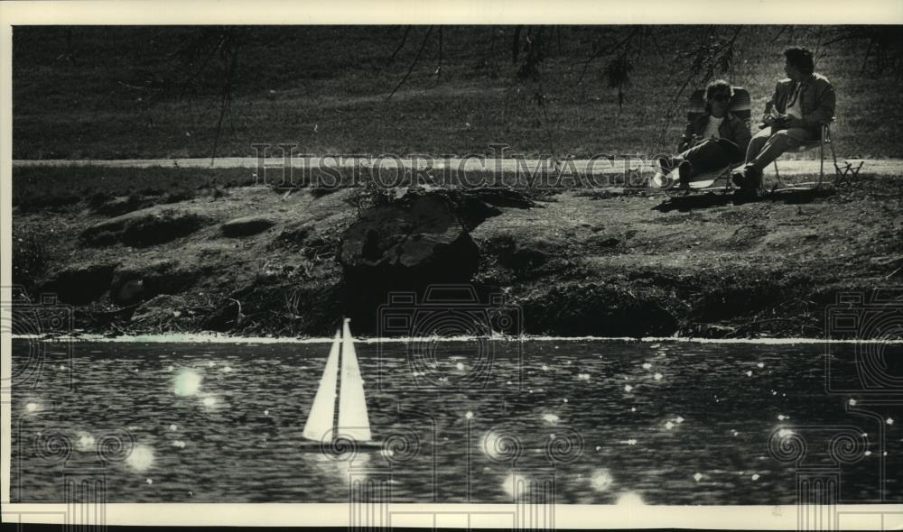 1988 Press Photo Couple on bank at Juneau Park Lagoon use radio-controlled boat - Historic Images