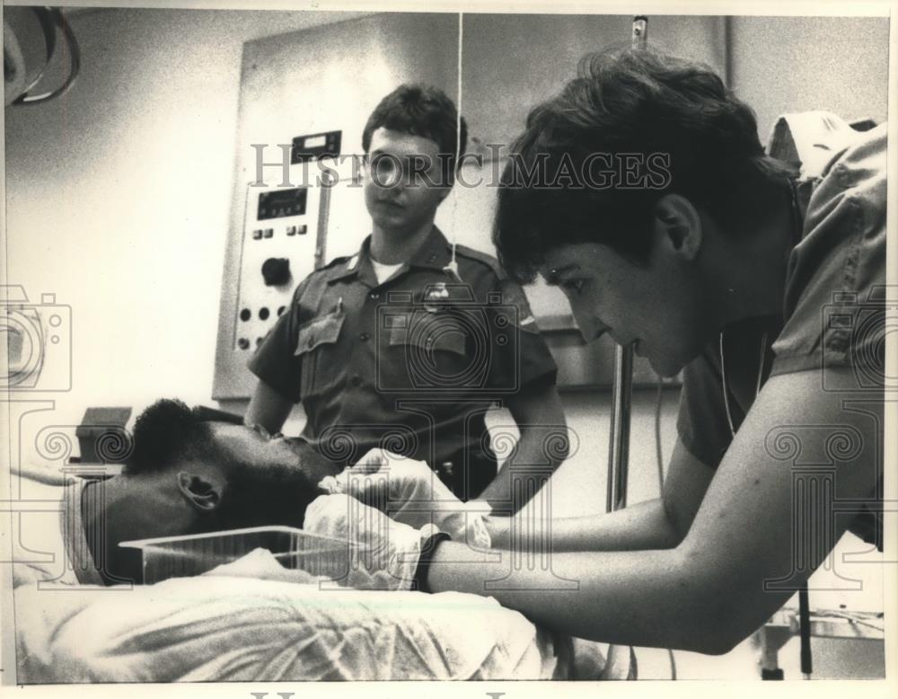 1988 Press Photo Nurse treats head wound as police watch, Oklahoma Memorial Hosp - Historic Images