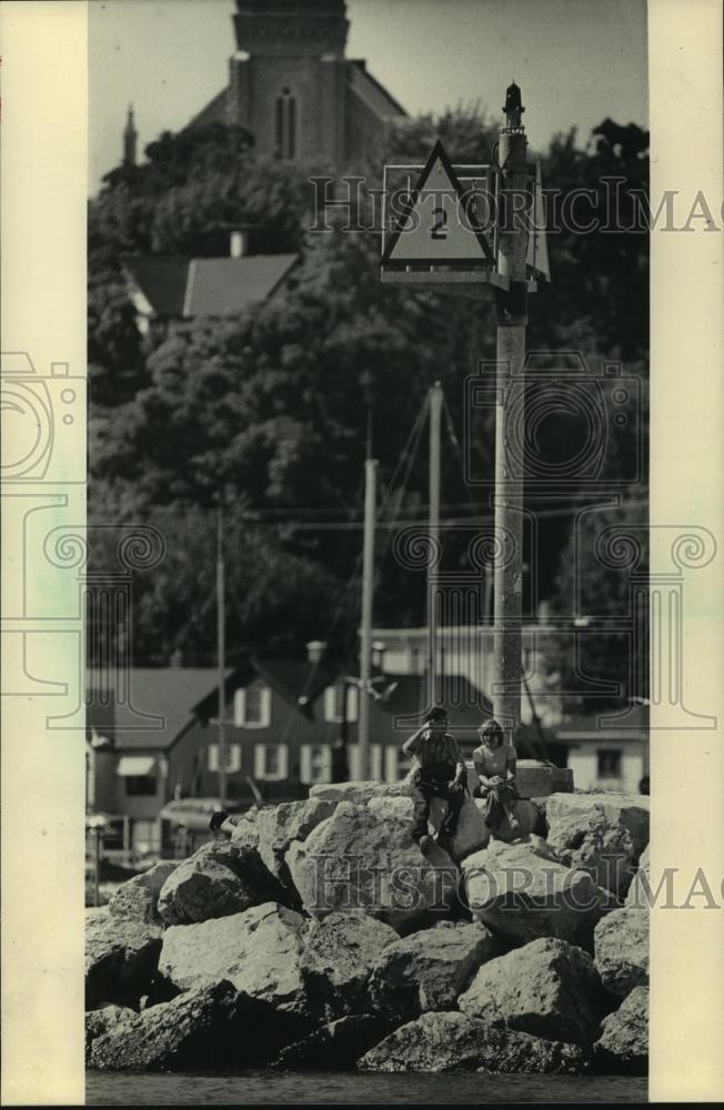 1984 Press Photo Couple sits on rocks at Marina in Port Washington - mjb90196 - Historic Images