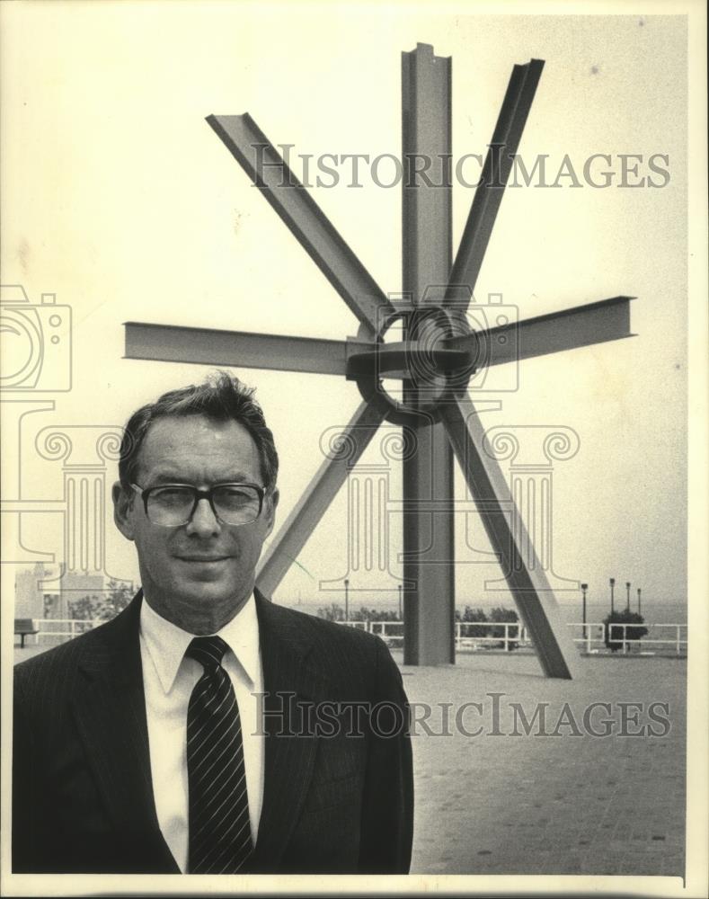 1985 Press Photo John D. Roethle standing in front of a large metal sculpture. - Historic Images