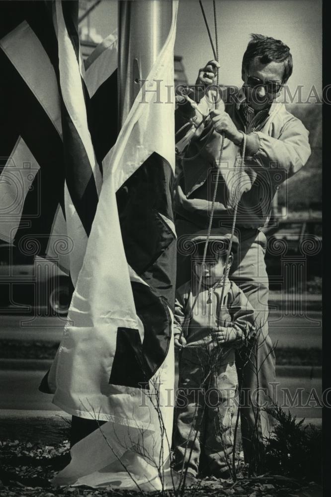 1986 Press Photo M &amp; L Bank President Robert A. Schmidt and son Robby raise flag - Historic Images