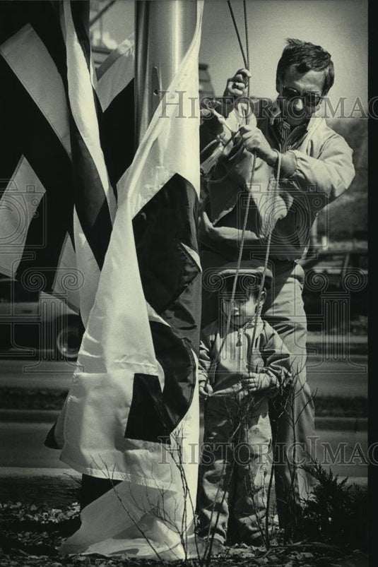 1986 Press Photo M & L Bank President Robert A. Schmidt and son Robby raise flag - Historic Images