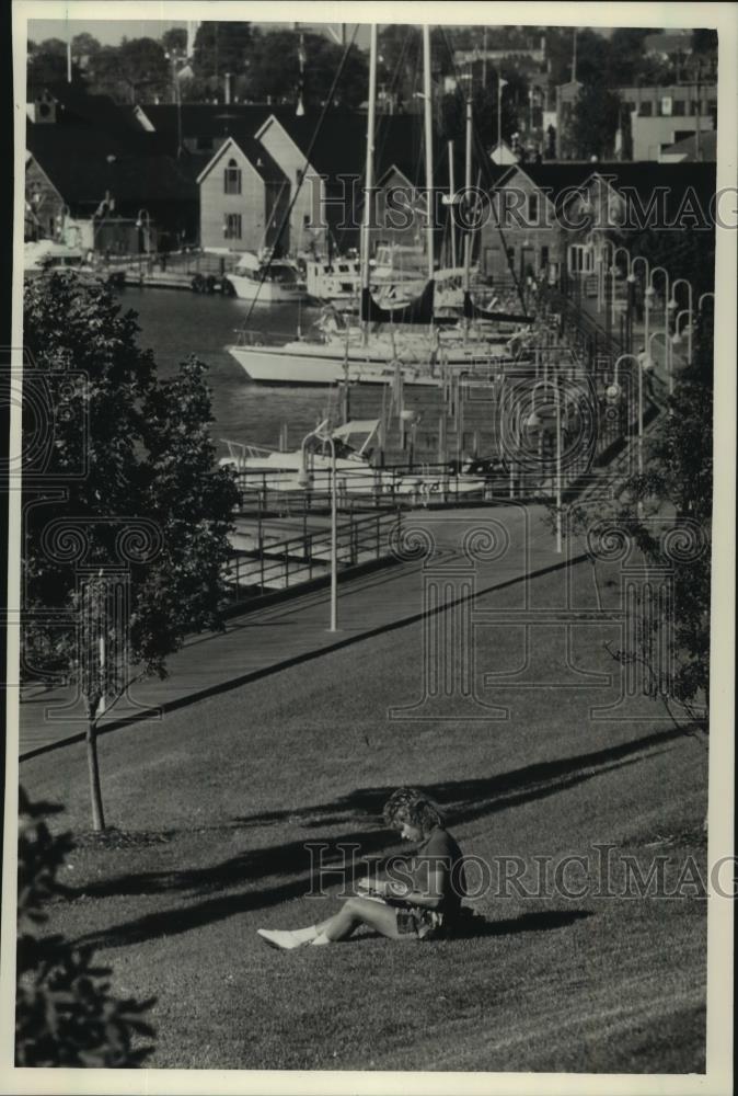 1988 Press Photo Woman reads with view of Sheboygan&#39;s harbor, Wisconsin - Historic Images