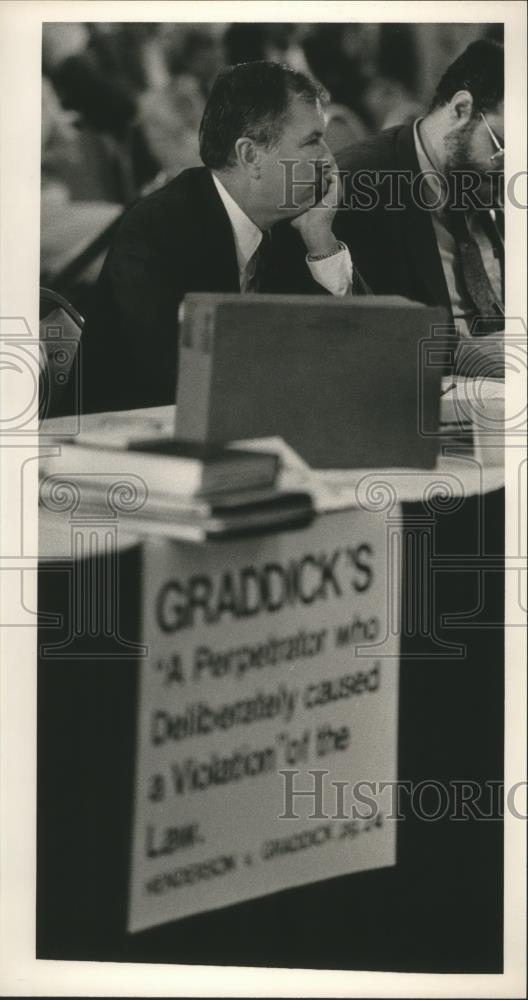 1986 Press Photo Baxley sits in front of sign about Graddick in Alabama - Historic Images