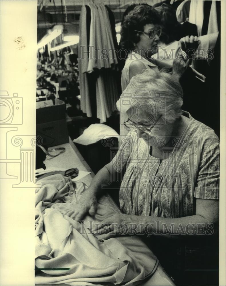 1983 Press Photo Rose Salamone checks for sewing flaws in a finished garment - Historic Images