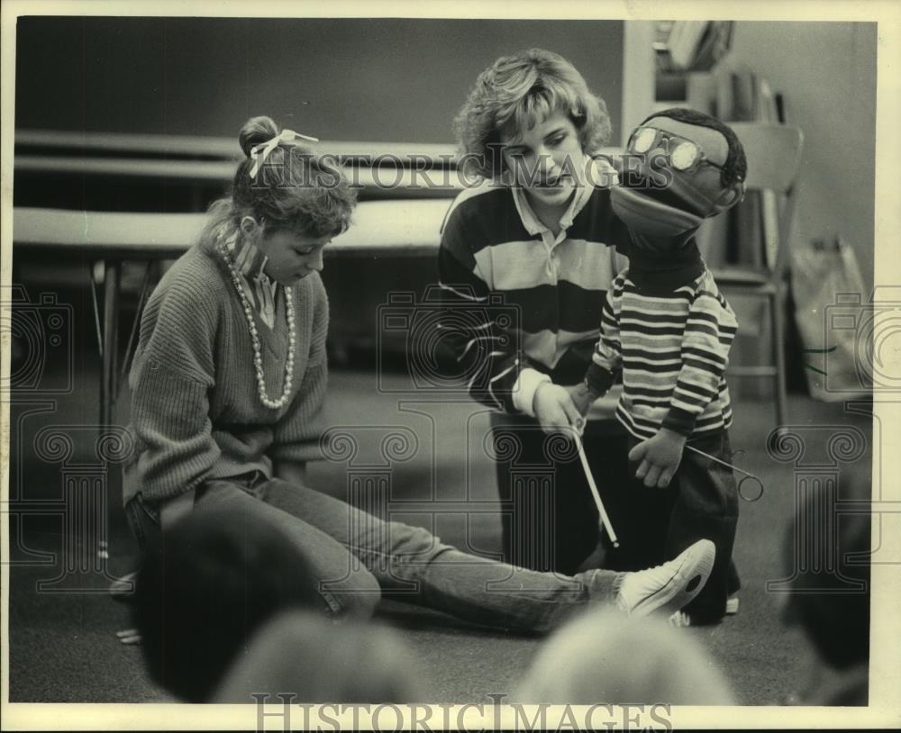 1985 Press Photo Carlene Kaplan led blind puppet over Kay Silverwood&#39;s leg - Historic Images