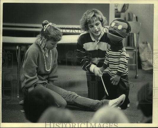 1985 Press Photo Carlene Kaplan led blind puppet over Kay Silverwood's leg - Historic Images