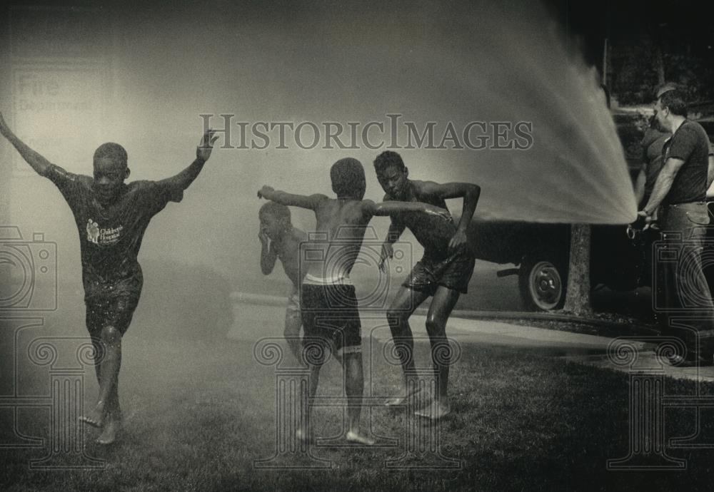 1992 Press Photo Firefighter Phil Jones help kids beat the heat, Milwaukee. - Historic Images