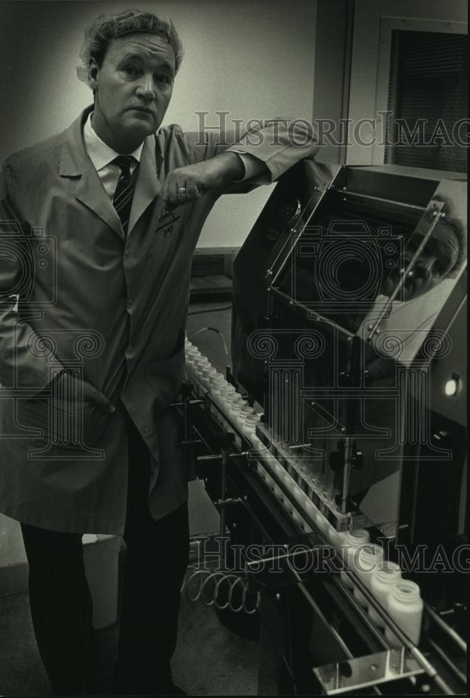 1990 Press Photo Ian Troup stands next to a pill loading machine in Mequon - Historic Images