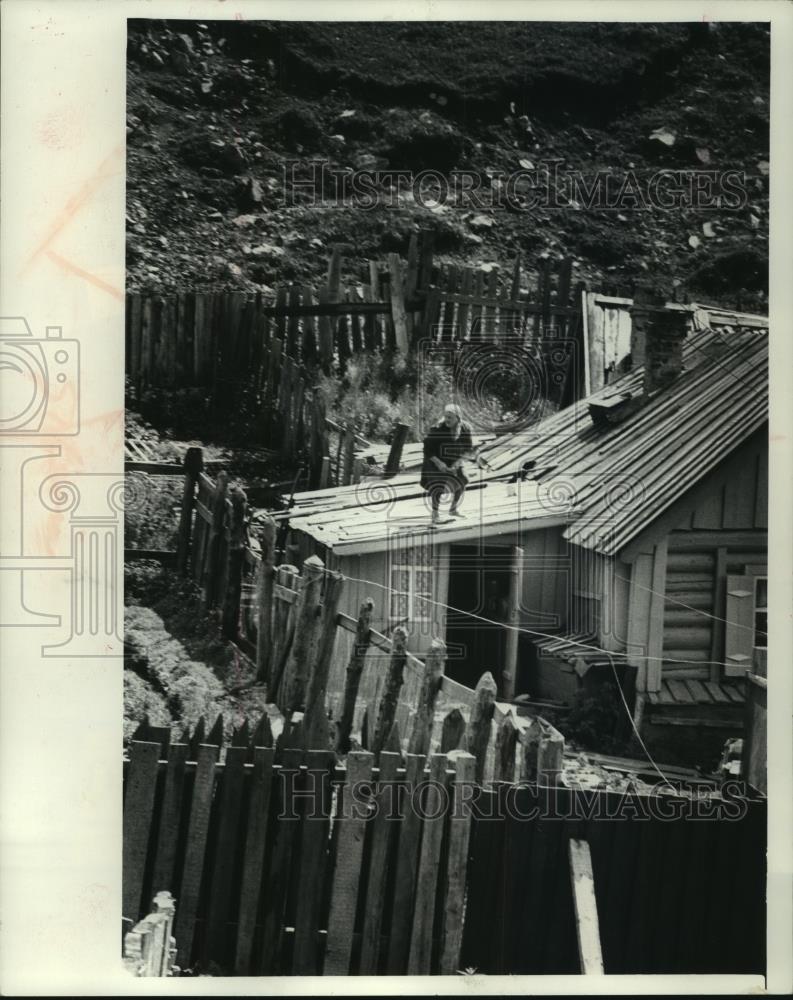 1978 Press Photo A woman repairs roof of house in Listvyanka, Siberia, Russia - Historic Images