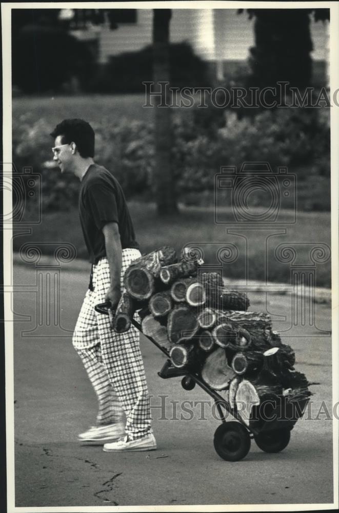 1991 Press Photo Tony Drew carts off wood from storm damaged tree, Wisconsin - Historic Images