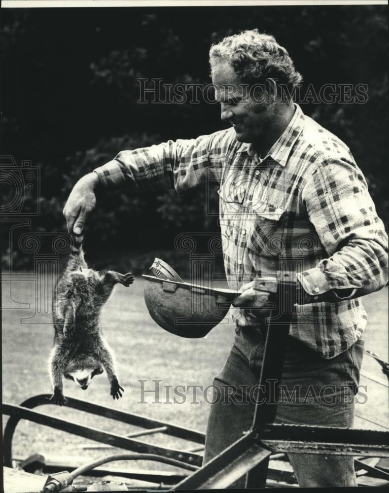 1989 Press Photo John Homontowski rescued a raccoon from debris, Thienville, WI. - Historic Images