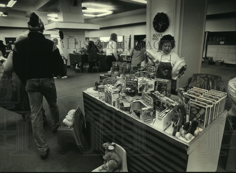 1989 Press Photo Toys 4 Tots worker arranged table at Mitchell St. Mall Toy Shop - Historic Images