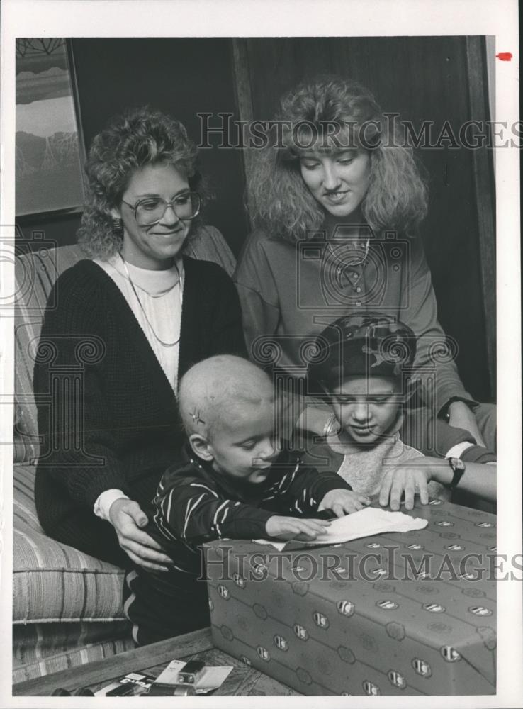 1987 Press Photo Volunteers watch young boys open toys from Gifts Inc. - Historic Images