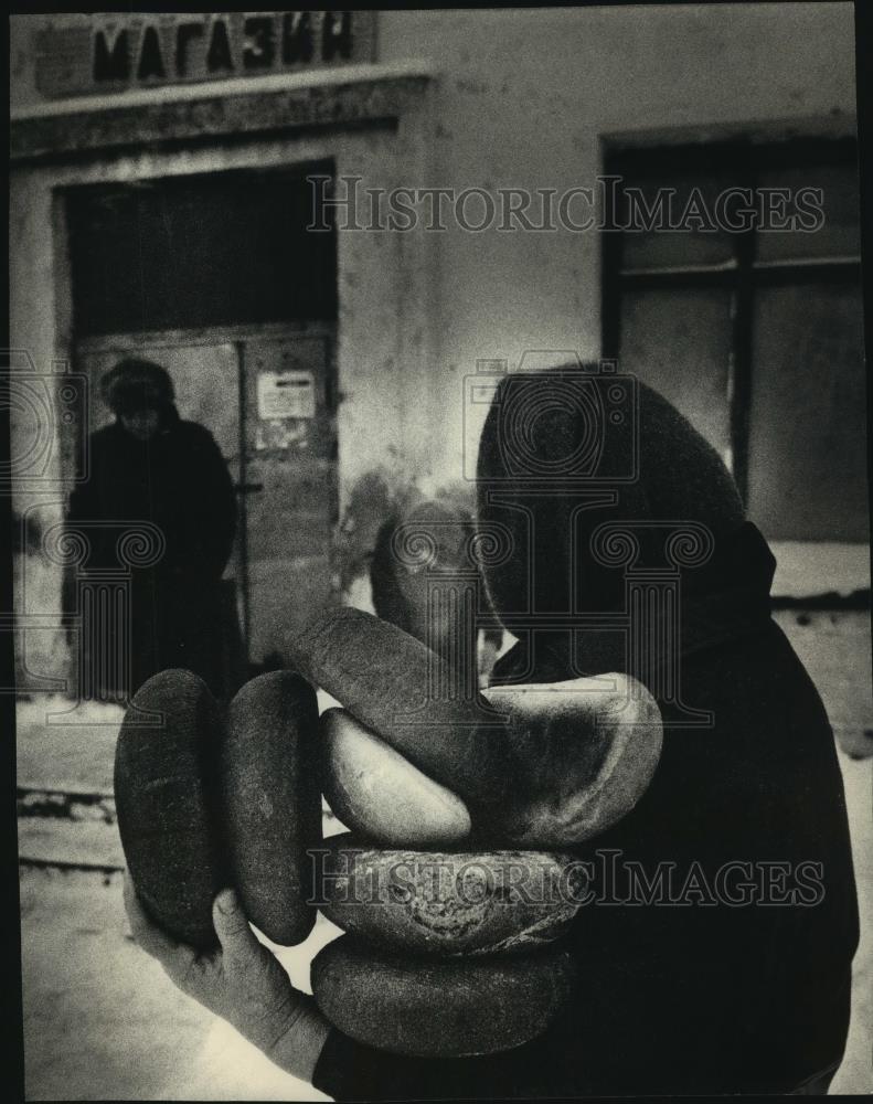 1992 Press Photo Woman takes too many loaves from store Sukhodol Russia - Historic Images