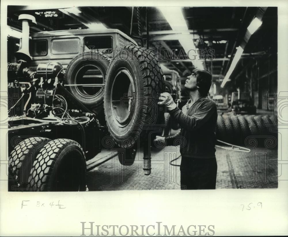 1977 Press Photo Worker Handles Tire in Production Line of Kamaz Trucks, Russia - Historic Images