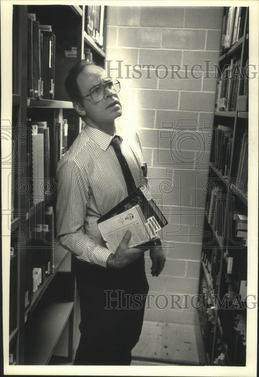 1992 Press Photo Lawrence D. Lynch looks at book collection, UW-Eau Claire - Historic Images