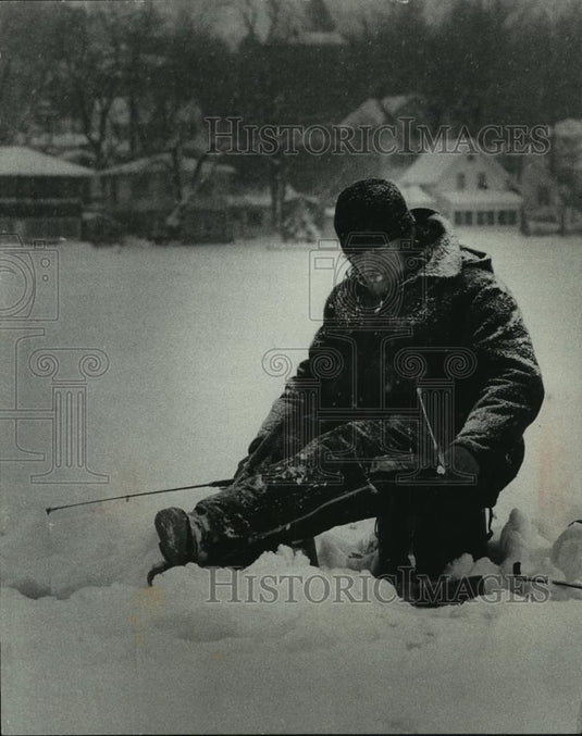 1977 Press Photo Brian Amundson, ice fishing in the snow, Pewaukee Lake, WI - Historic Images