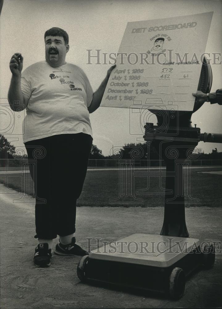 1986 Press Photo David Schultz with a large scale showing weight loss, Milwaukee - Historic Images